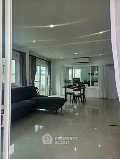 Spacious modern living room with sleek tile flooring and large windows for natural light.