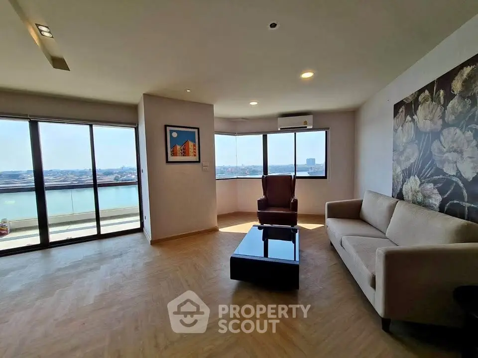 Spacious living room with panoramic windows and elegant decor overlooking a serene water view.
