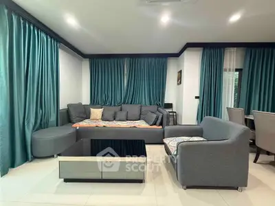 Spacious living room with modern gray furniture and elegant teal curtains, perfect for relaxation and entertainment.