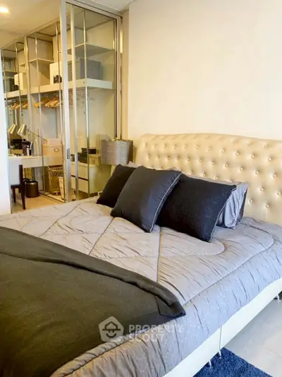 Luxurious bedroom with plush bedding and mirrored closet doors in modern apartment.