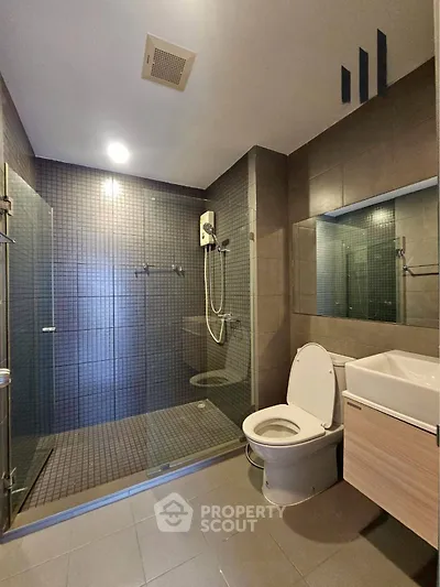 Modern bathroom with glass shower enclosure and sleek fixtures in a contemporary apartment.
