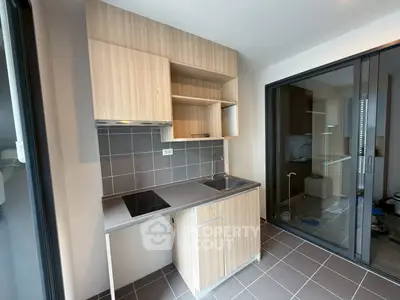 Modern compact kitchen with sleek cabinetry and electric cooktop in a stylish apartment.