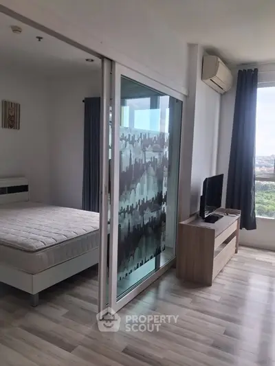Modern bedroom with sliding glass door and scenic view, featuring sleek furniture and air conditioning.