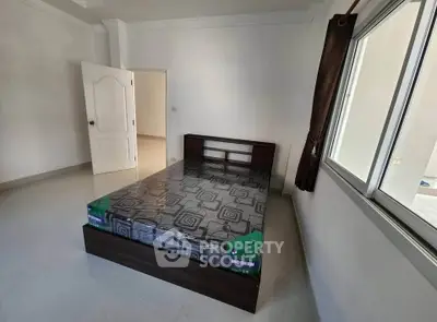 Spacious bedroom with modern bed and large window offering natural light.