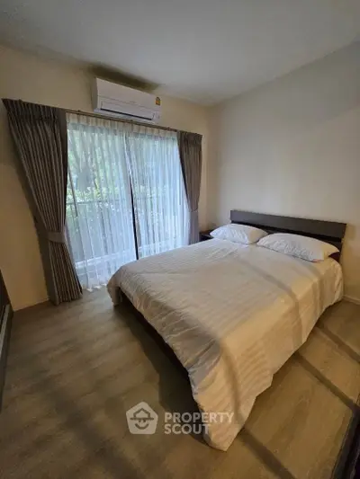 Cozy bedroom with large window and air conditioning, featuring elegant curtains and a comfortable bed.