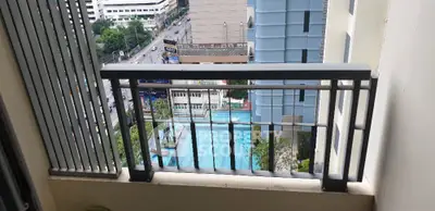 High-rise balcony with city view overlooking a swimming pool, perfect for urban living.