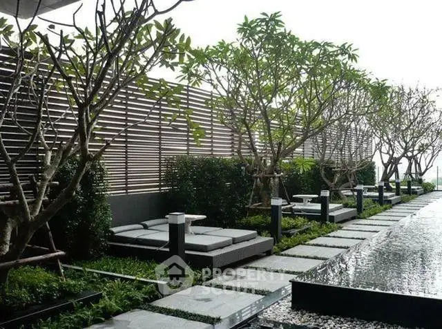Luxurious outdoor garden with modern lounge chairs and water feature in a serene setting.