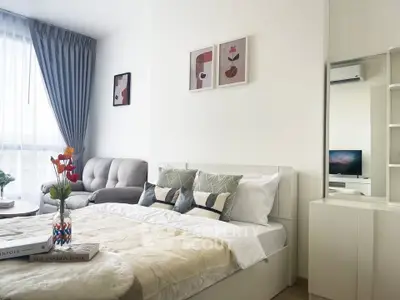 Modern bedroom with cozy decor and natural light, featuring a stylish sofa and elegant wall art.