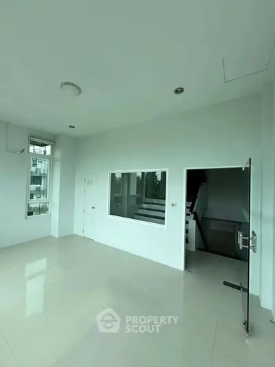 Spacious modern room with large windows and glass door, ideal for versatile living space.