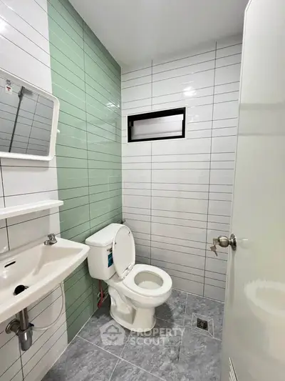 Modern bathroom with sleek tiles and compact design, featuring a toilet and sink.