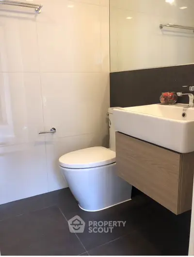 Modern bathroom with sleek fixtures and minimalist design, featuring a wall-mounted sink and toilet.