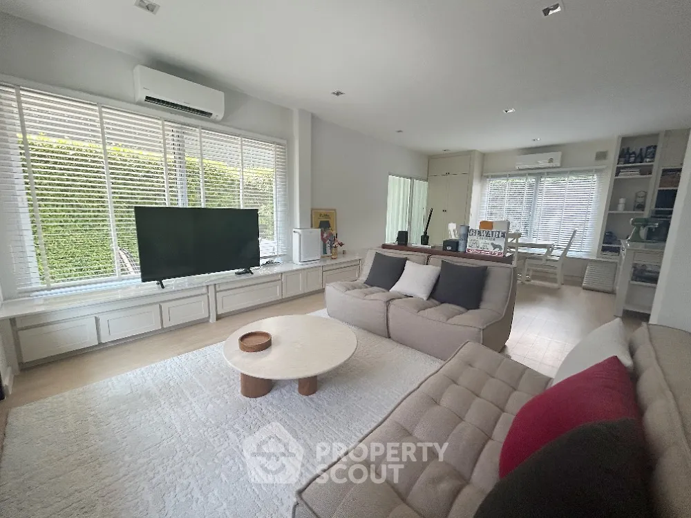 Spacious and elegantly appointed living room with abundant natural light, modern furniture, and a seamless flow into the dining area, perfect for entertaining and relaxation.