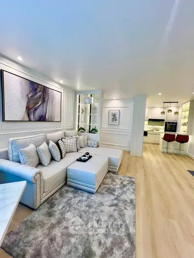 Luxurious open-plan living room with modern kitchen, elegant decor, and cozy seating area.