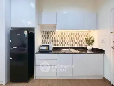 Modern kitchen with sleek cabinetry, black countertop, and stylish backsplash in a contemporary apartment.