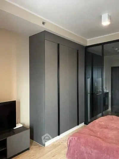 Modern bedroom with sleek wardrobe and glass partition, featuring cozy decor and contemporary design.