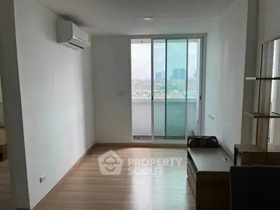 Spacious living room with large window and city view in modern apartment.