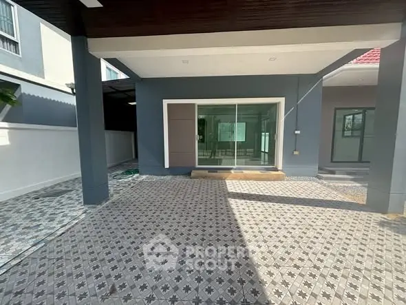 Spacious modern home entrance with stylish tiled flooring and large glass doors.