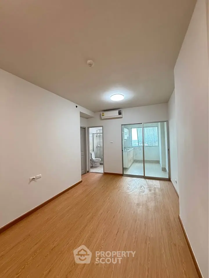 Spacious empty room with wooden flooring and sliding glass doors