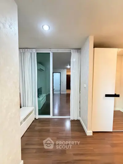 Spacious modern apartment interior with wooden flooring and sliding glass doors.