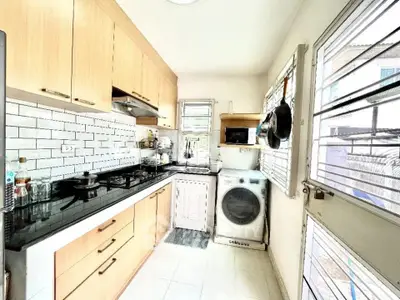 Modern kitchen with gas stove, washing machine, and ample storage space.