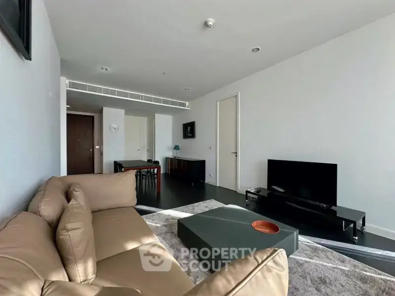 Modern living room with sleek furniture and open layout, featuring a comfortable sofa and large TV.