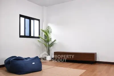 Minimalist living room with wooden floor, bean bag, and potted plant, perfect for modern lifestyle.