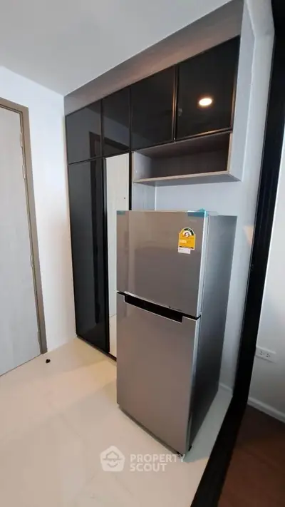 Modern kitchen with sleek fridge and stylish cabinetry in a contemporary apartment.