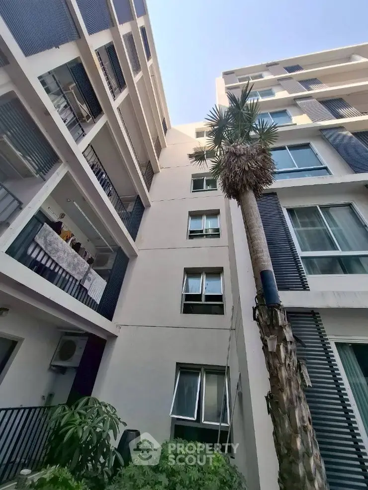 Modern apartment building exterior with sleek architectural design and lush greenery.