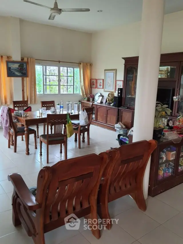Spacious and inviting living area with elegant wooden furniture, large windows, and a cozy dining space, perfect for family gatherings.