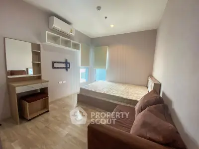 Cozy bedroom with wooden flooring, featuring a bed, sofa, and wall-mounted TV bracket.