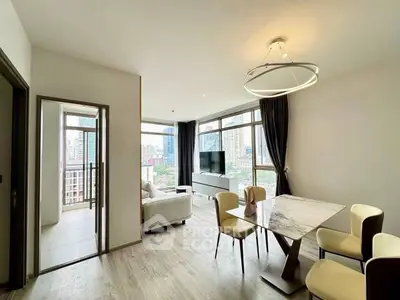 Modern open-plan living and dining area with city view, stylish furniture, and elegant lighting.