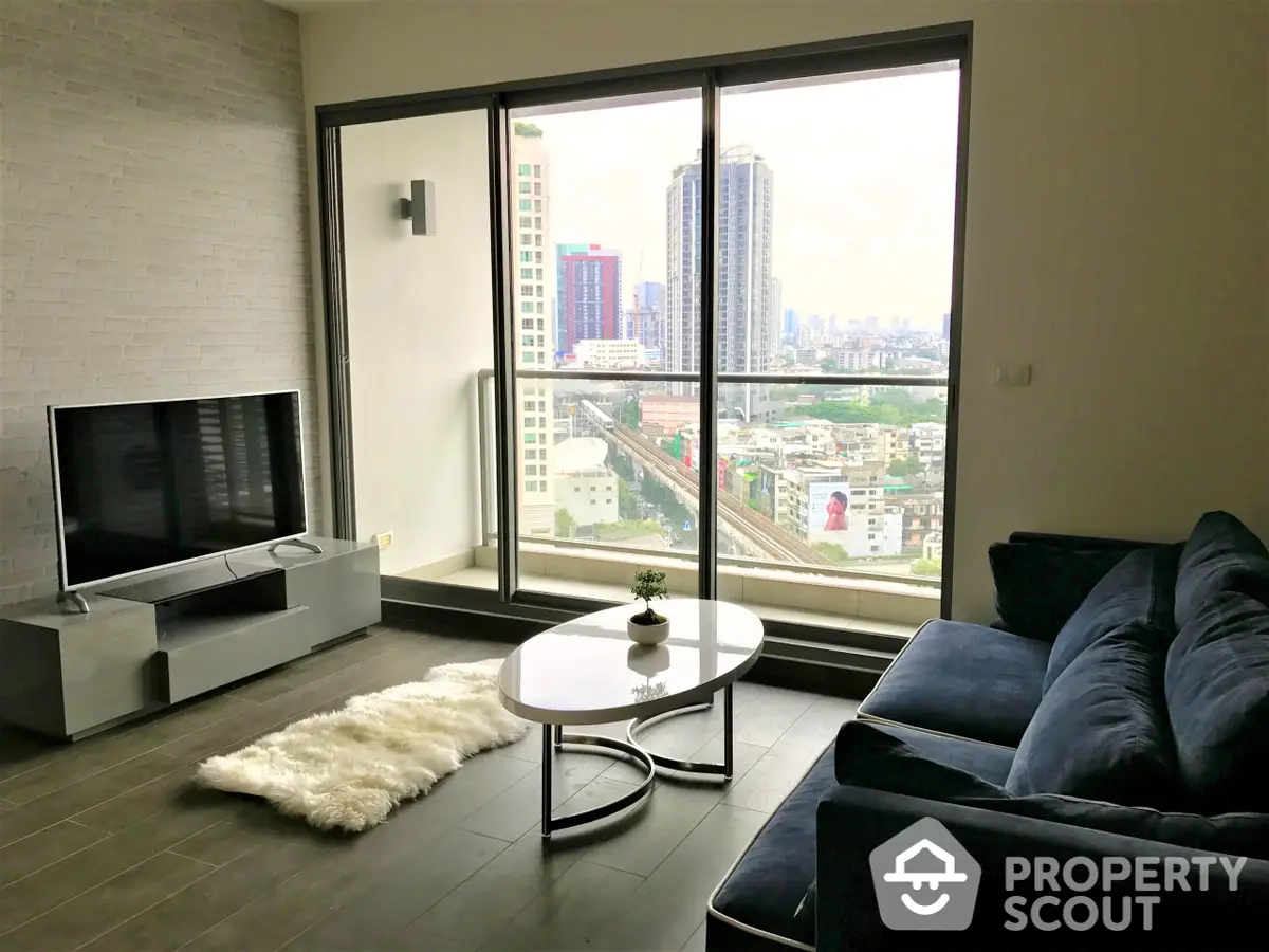 Spacious living room with modern furnishings, large windows offering panoramic city views, and abundant natural light, perfect for urban living.