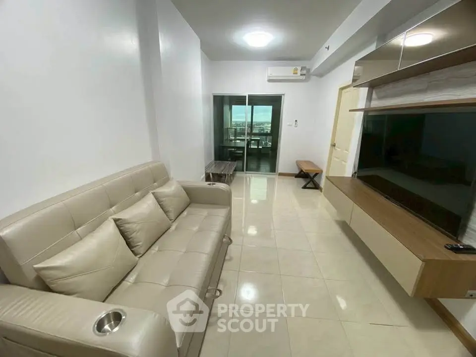 Modern living room with sleek furniture and large TV, featuring a bright and airy atmosphere.