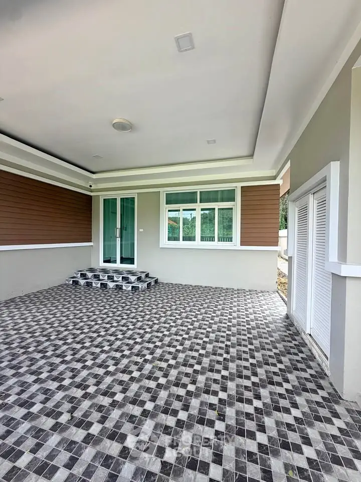 Modern home exterior with stylish tiled patio and glass door entrance.