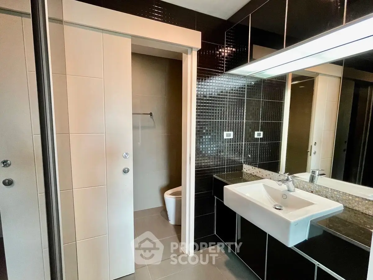 Modern bathroom with sleek black tiles and large mirror