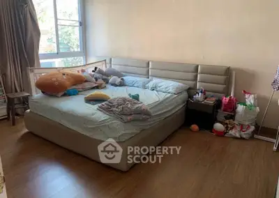 Cozy bedroom with large bed and plush toys, featuring natural light from a window.