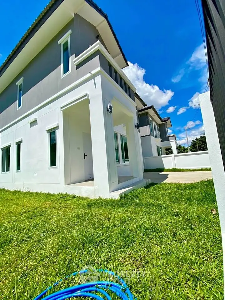 Modern two-story house with lush green lawn under a clear blue sky.