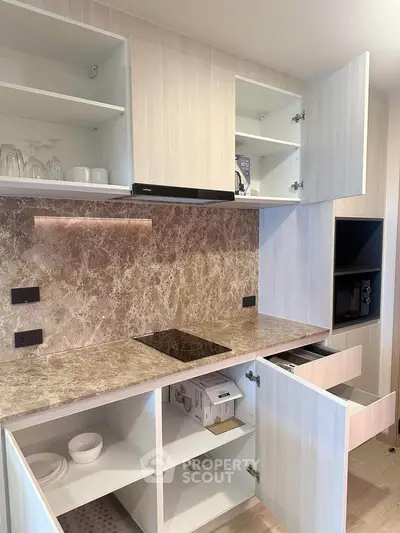 Modern kitchen with open cabinets and marble backsplash in a stylish apartment.