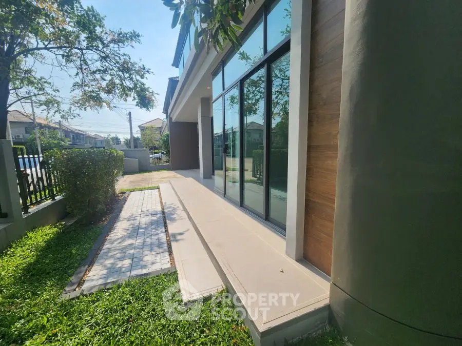 Modern house exterior with large windows and lush green garden