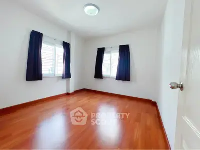Spacious empty bedroom with wooden flooring and large windows