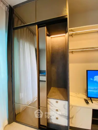Modern bedroom with sleek wardrobe and TV unit, featuring elegant design and ample storage space.