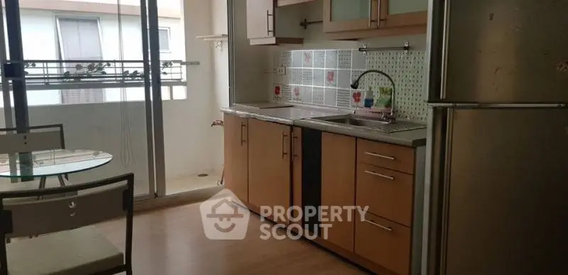 Modern kitchen with balcony access, featuring sleek cabinets and stainless steel appliances.