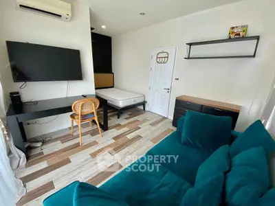 Modern living room with teal sofa, wall-mounted TV, and stylish workspace.