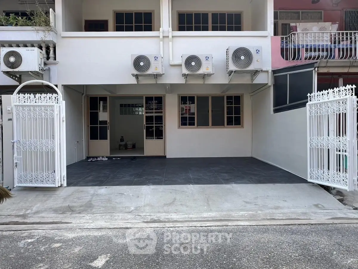 Spacious townhouse entrance with gated parking and air conditioning units