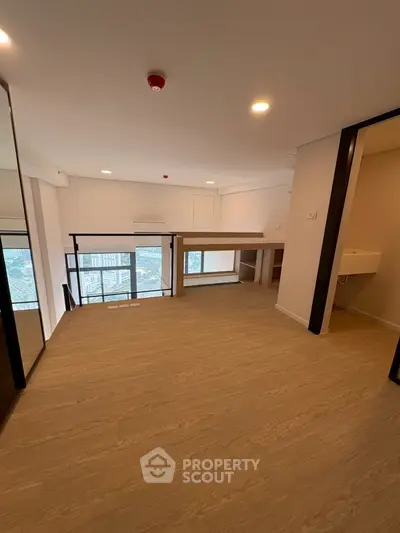 Spacious modern living room with wooden flooring and large windows offering city views.