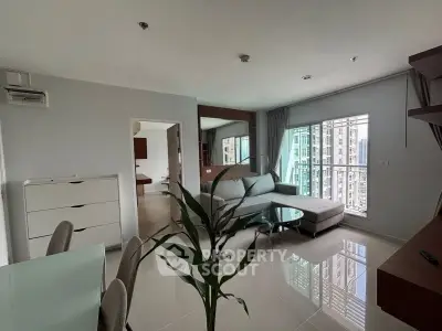 Modern living room with large windows and city view, featuring sleek furniture and glossy tiled floors.