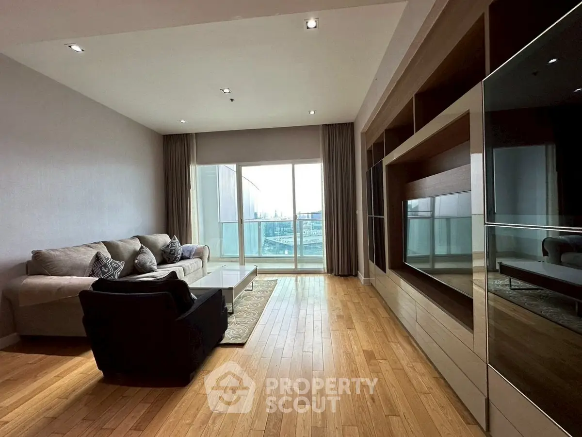 Spacious modern living room with hardwood floors and large windows offering a stunning city view.