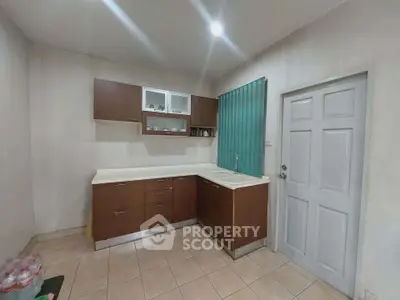 Modern kitchen with sleek cabinetry and tiled flooring, featuring a minimalist design and ample storage space.