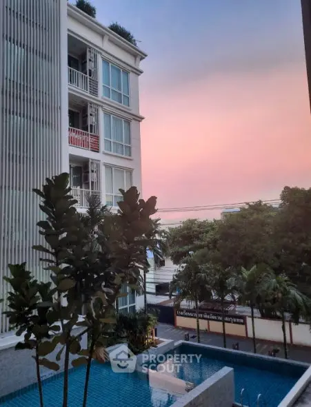 Modern apartment building with pool and sunset view, ideal for luxury living.