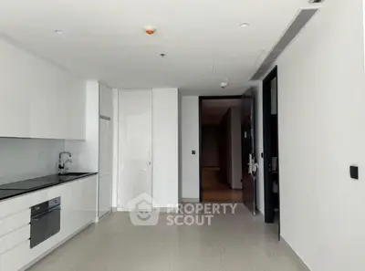 Modern minimalist kitchen with sleek white cabinetry and built-in appliances in a bright apartment.
